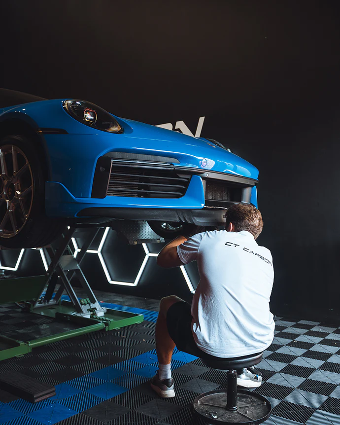 man installing carbon fibre on blue car