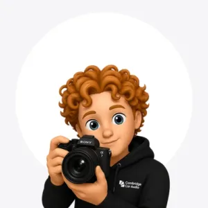 Cartoon avatar with curly red hair wearing a black Cambridge Car Audio hoodie, holding a Sony camera up as if taking a photo.